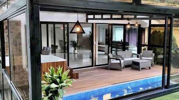 A modern outdoor living area with a pool, glass walls, and outdoor furniture. - The Provenza Mansion by Lleras Park in El Poblado (Medellín)