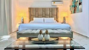 A modern hotel room with a large bed, two bedside lamps, a glass coffee table with decorative items, and a painting on the wall. - The Provenza Mansion by Lleras Park in El Poblado (Medellín)