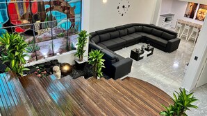 A modern living room with a black sectional sofa, a wooden coffee table, and a stained glass window with a painting.