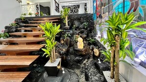 A modern indoor garden with a stone wall, wooden steps, and various potted plants.