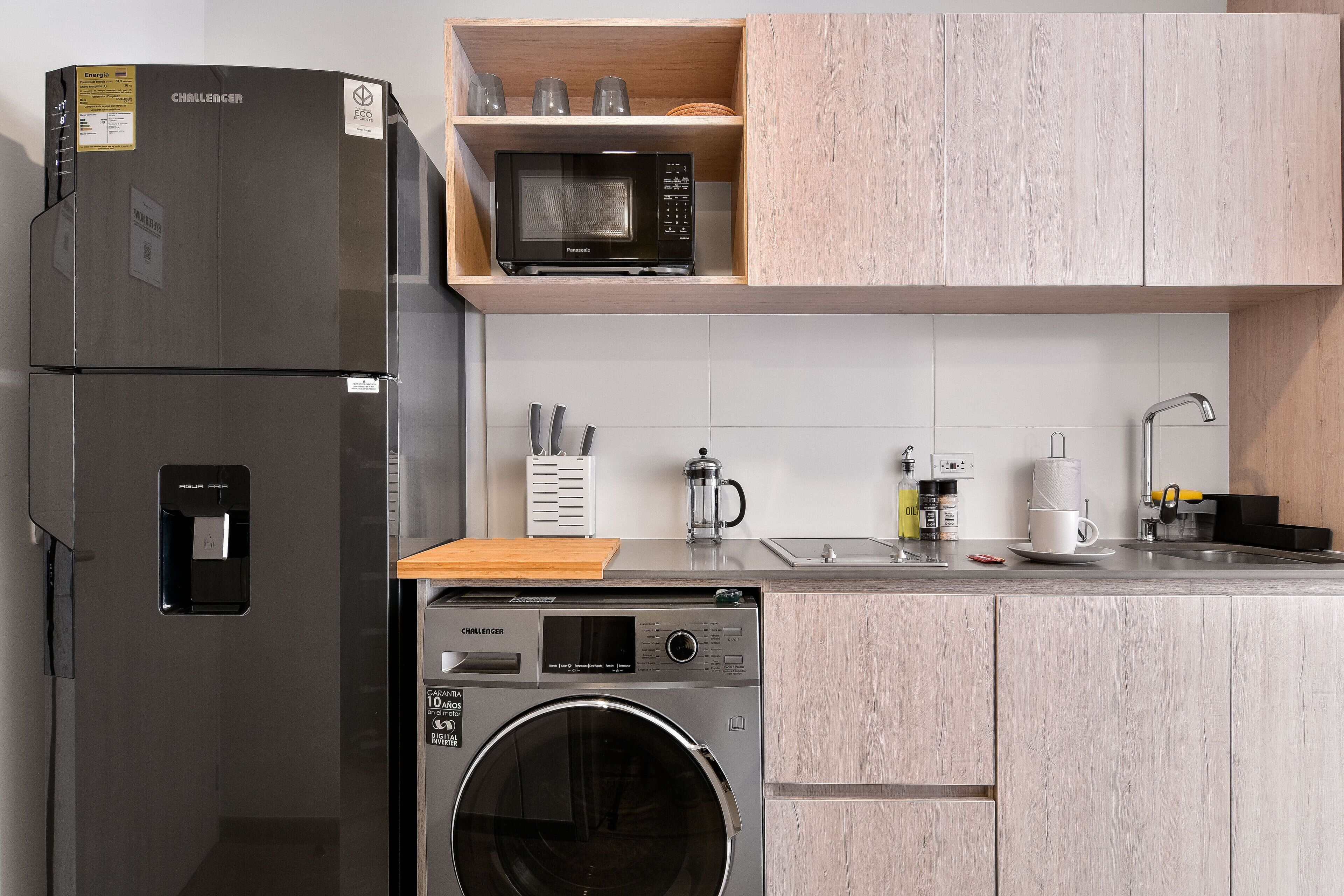 A compact kitchen with a refrigerator, microwave, and washing machine.