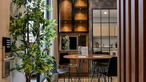 Een moderne keuken met houten kastjes, een eethoek met een ronde tafel en een potplant.