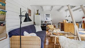 Un espacio habitable estilo loft acogedor con cama en un entrepiso, un sofá, una mesa de comedor y una zona de cocina.