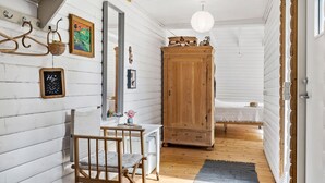 Un pasillo con un armario de madera, un espejo y una pequeña mesa con una silla.