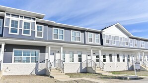 A multi-story residential building with a symmetrical facade, multiple windows, and a central entrance with steps.