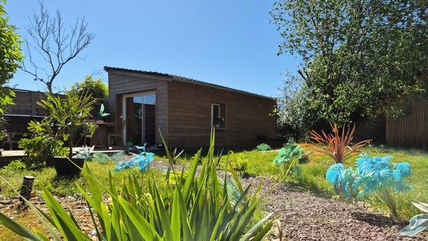A wooden house with a garden in front, including green plants and a gravel path. - Vila Sozinha Luxury (Escames)