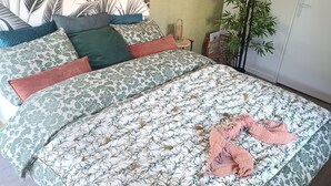 A bedroom with a bed, a green wall, a bamboo plant, and a wall with a leaf pattern. - Vila Sozinha Luxury (Escames)