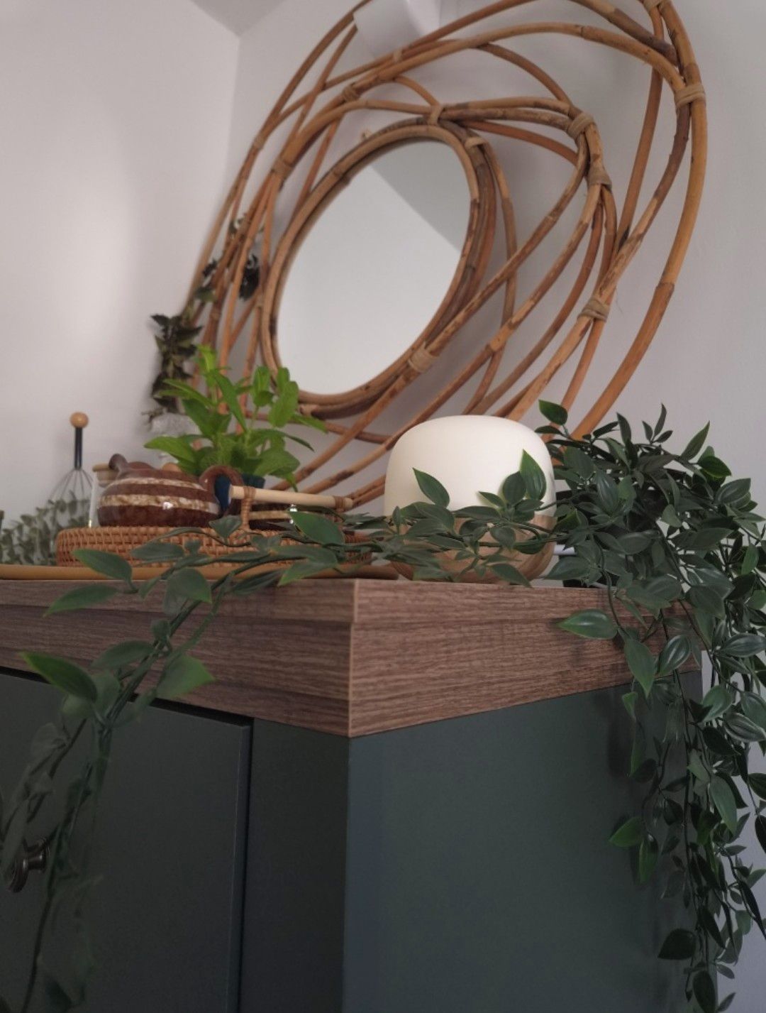 A room with a wooden cabinet, a woven circular structure, and a potted plant.