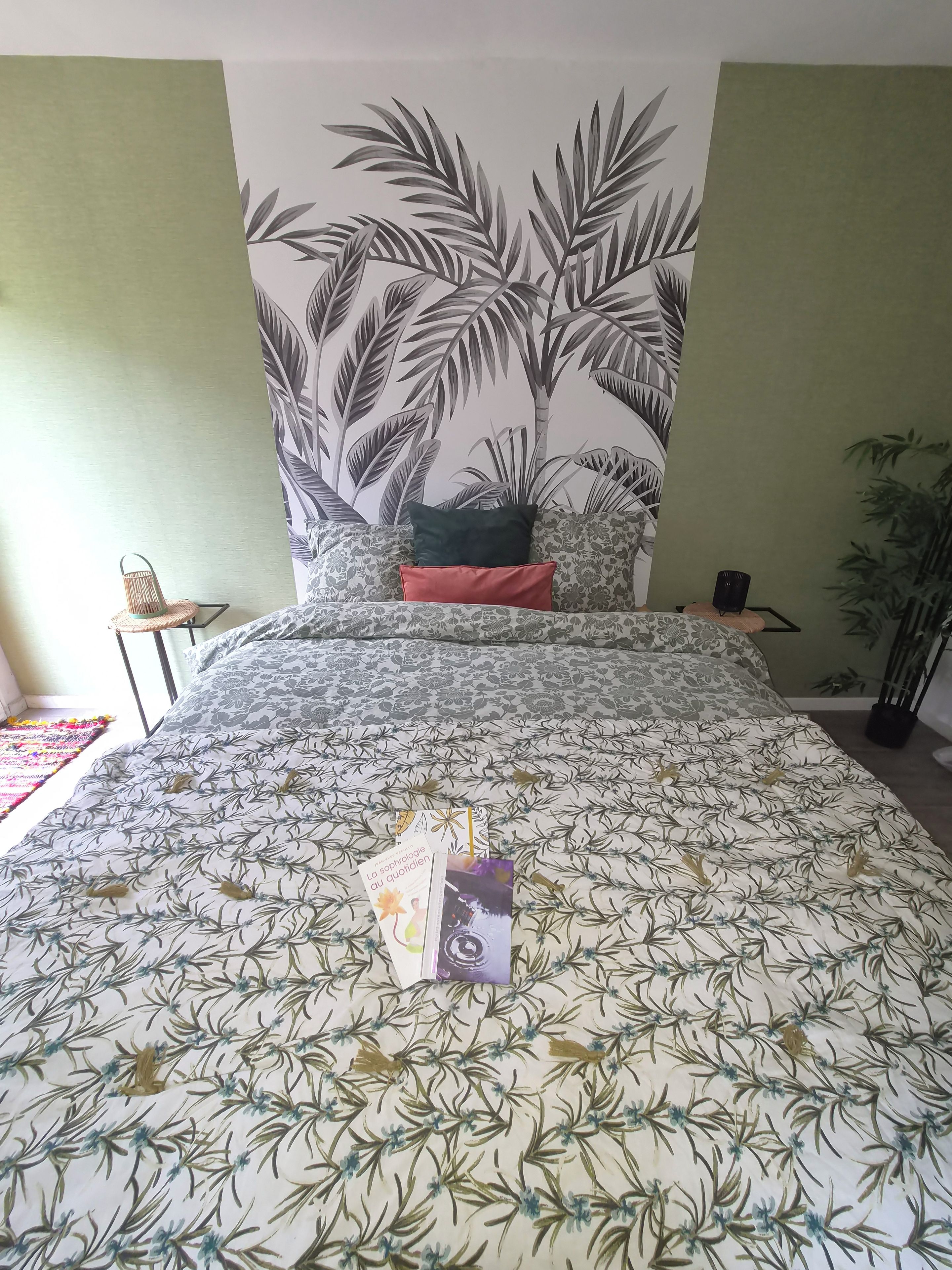 Una camera da letto con un letto, un affresco, un tavolino e una pianta in vaso.