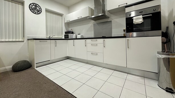 A modern kitchen with white cabinets, a stainless steel range hood, a microwave, and a toaster.