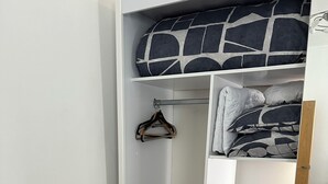A walk-in closet with hanging space, shelves, and a bed with patterned bedding.