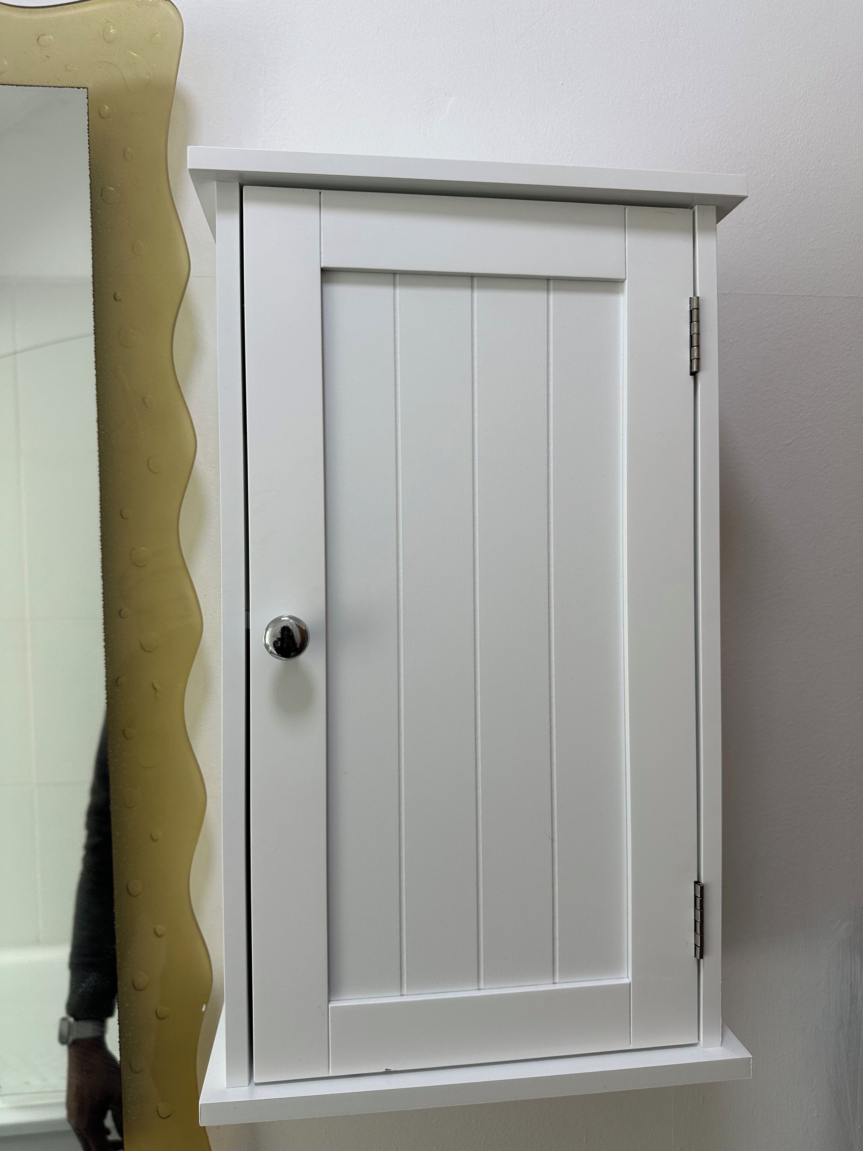 Ein weißer Schrank mit Tür, Griff und Schloss.