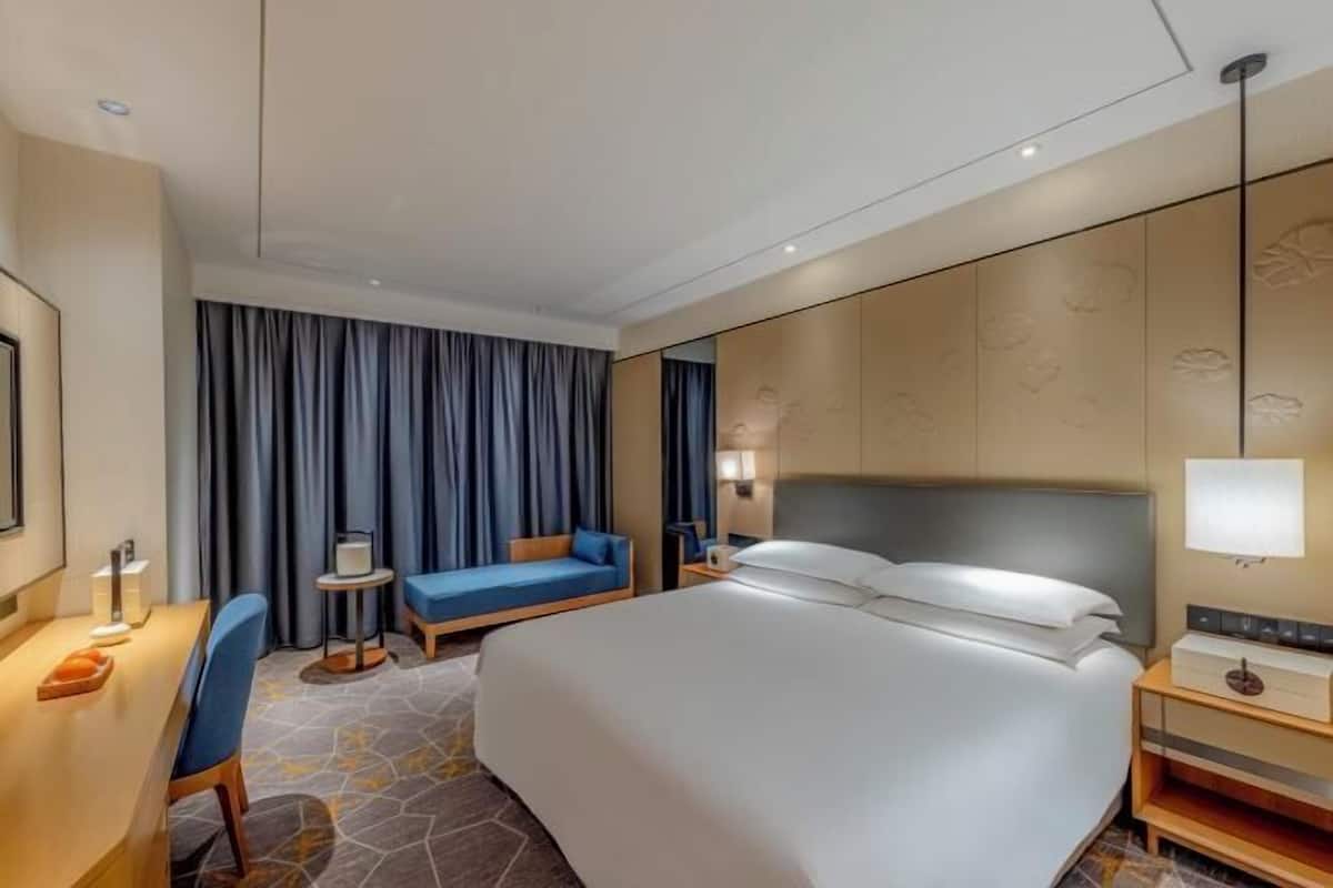 Una habitación de hotel con cama, escritorio, silla, una mesita y sofá.