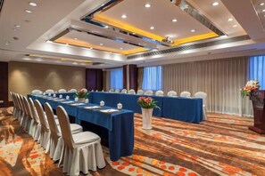 Un salón de conferencias con una larga mesa, sillas y piso alfombrado.