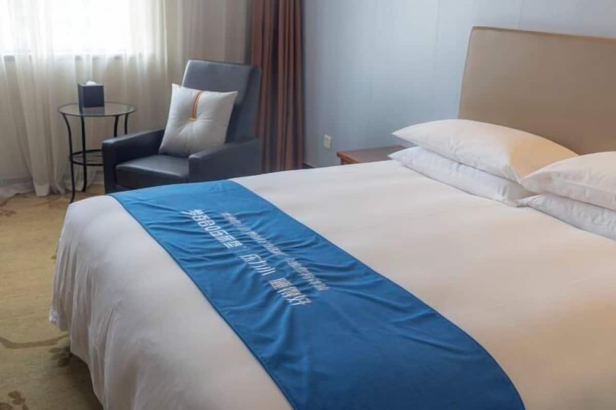 Una habitación de hotel con una cama, una silla, una mesita y una mesita de noche.