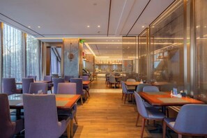 Un restaurante moderno con una barra larga, varias mesas y sillas. Se observa una zona de cocina al fondo.
