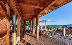 Une terrasse en bois avec une table et des chaises, offrant une vue sur un paysage magnifique.