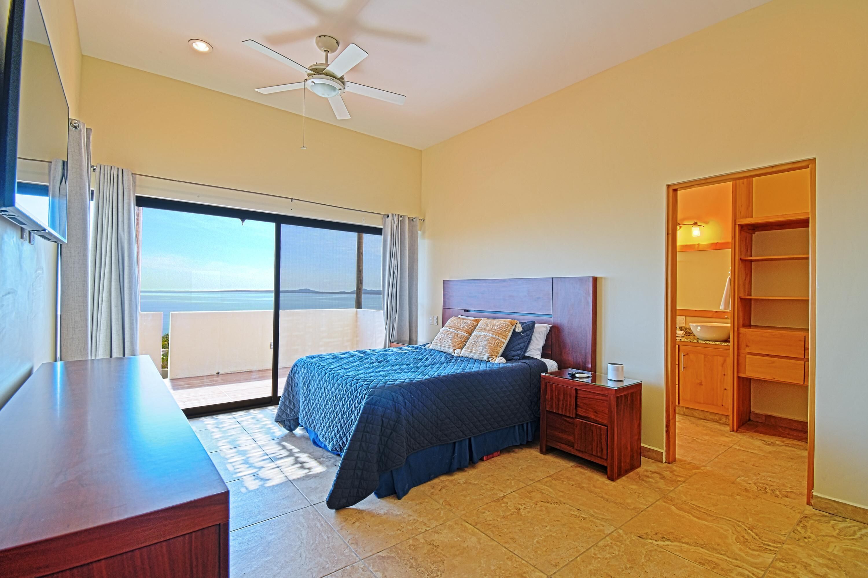 A bedroom with a bed, nightstand, wooden wardrobe, and a balcony with a view.