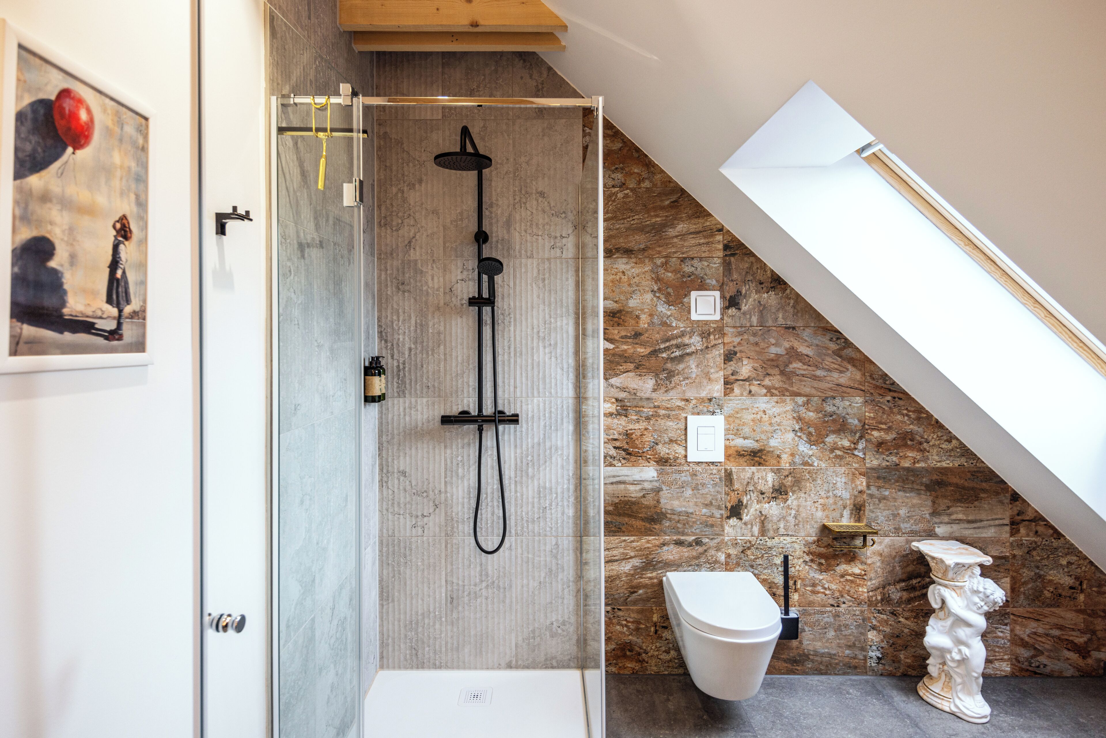 A modern bathroom with a glass-enclosed shower, a white toilet, and a stone wall.