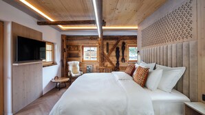 A bedroom with a large bed, wooden walls, a mounted TV, and a decorative wall panel.
