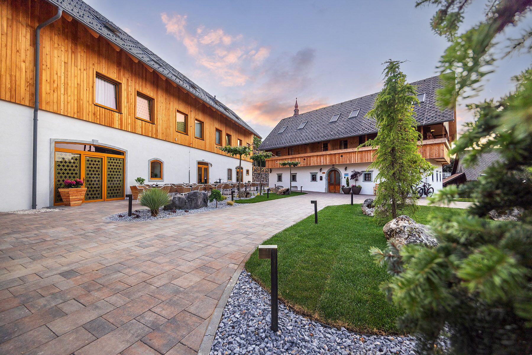 A courtyard with wooden buildings, outdoor seating, and a well-maintained lawn.