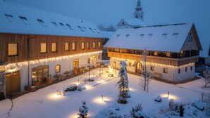 A snow-covered building with a large wooden facade and a church steeple in the background.