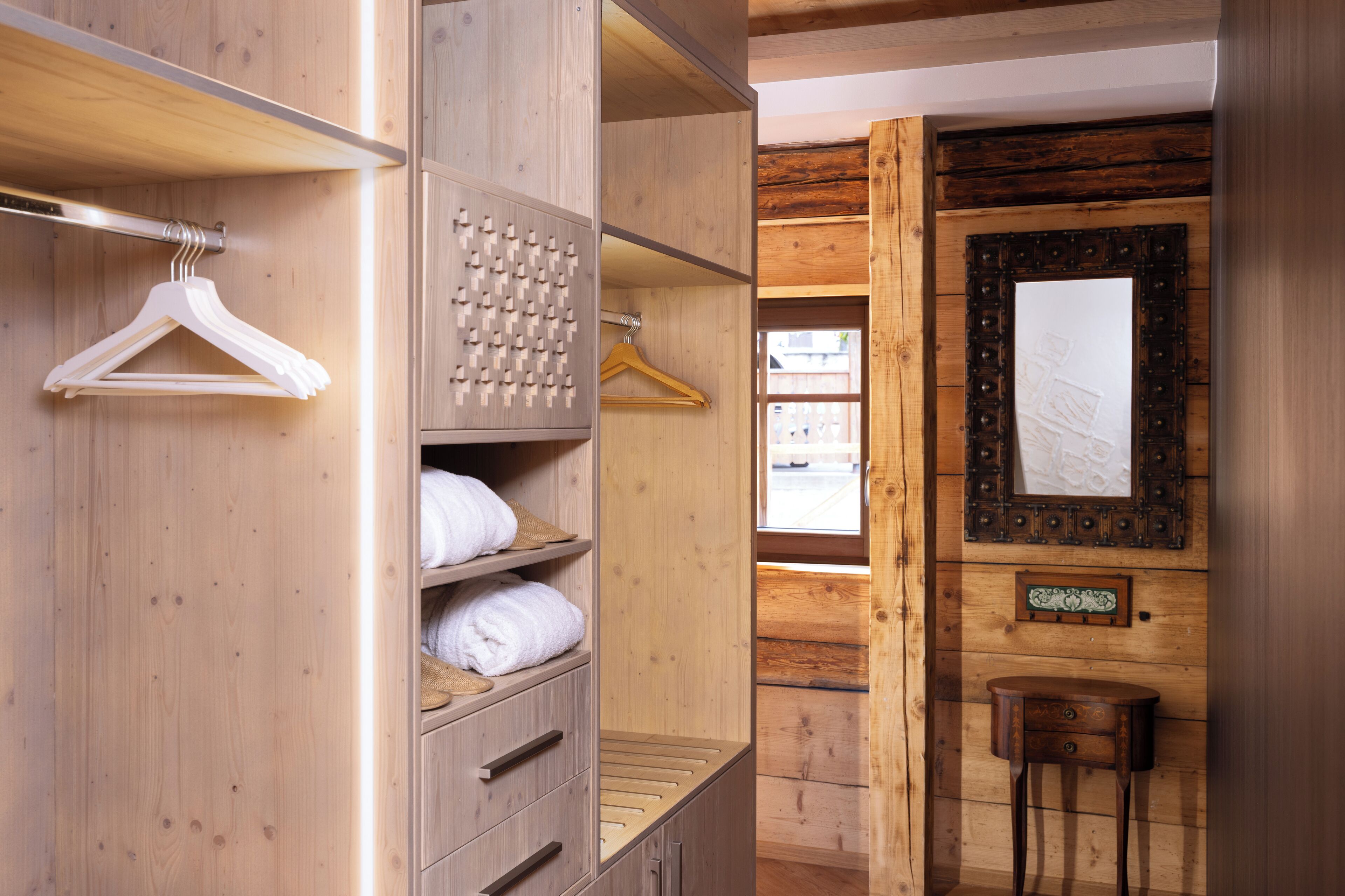 A wooden room with a wardrobe, a mirror, and a small table.
