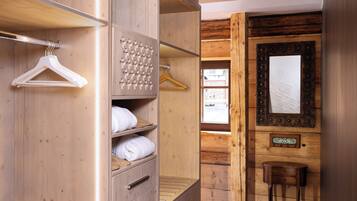 A wooden room with a wardrobe, a mirror, and a small table.