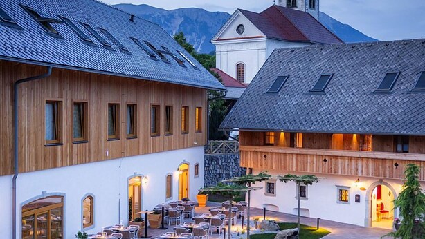 A traditional European village with wooden buildings, a church with a clock tower, and outdoor seating areas.