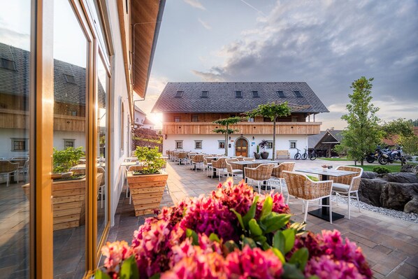 A traditional European-style building with a wooden facade, outdoor seating area with wicker furniture, and a stone pathway.