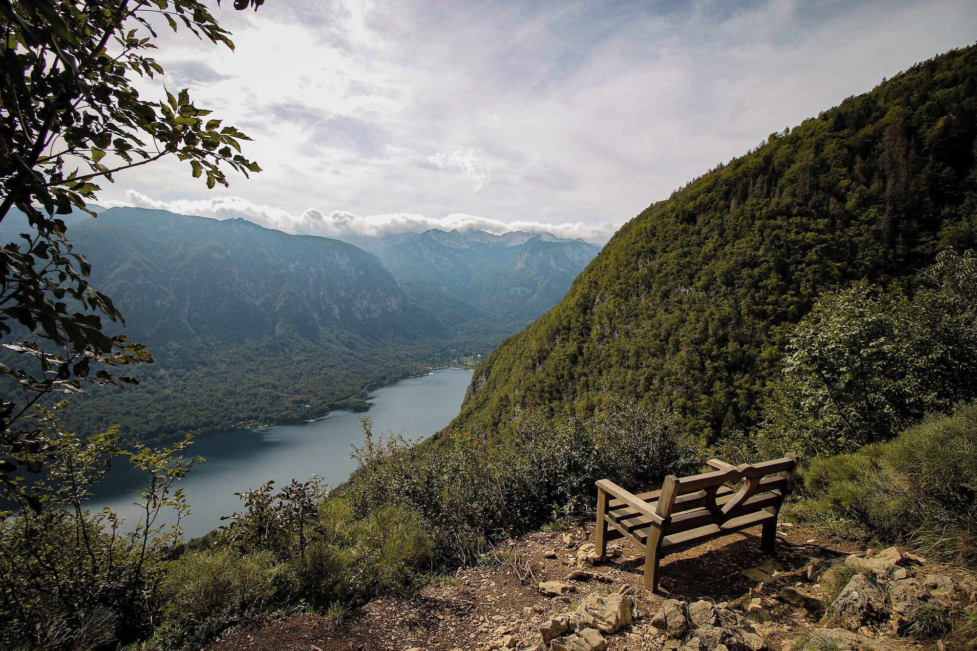 Eine Bank mit Blick auf einen See und Berge im Hintergrund.