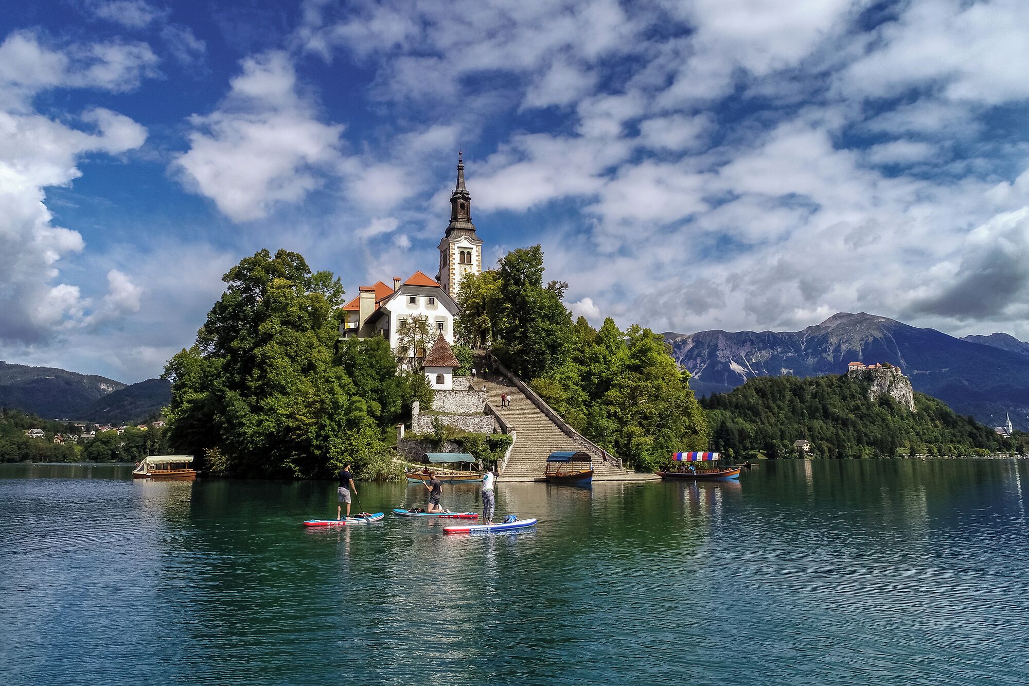 Ein historisches Gebäude mit einem Turm auf einer kleinen Insel, umgeben von Wasser und Bergen.