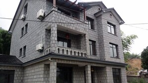 A two-story house with a stone facade, multiple windows, and a balcony. - Moganshan Yashan Inn (Deqing)