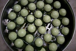 A tray of green spherical objects arranged in a grid pattern. - Moganshan Yashan Inn (Deqing)
