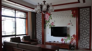 A traditional-style living room with a sofa set, a dining table, and a flat-screen TV mounted on the wall. - Moganshan Yashan Inn (Deqing)