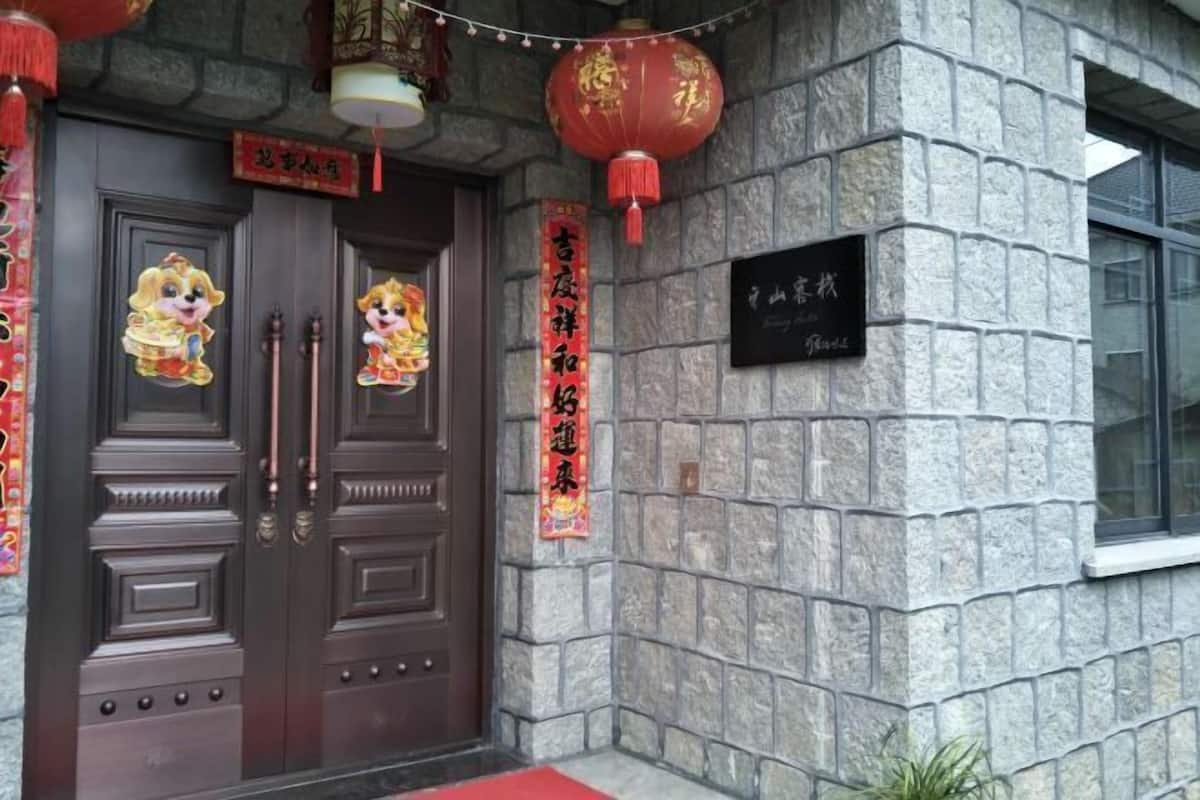 A stone building with a dark wooden door, red lanterns, and a sign with Chinese characters.