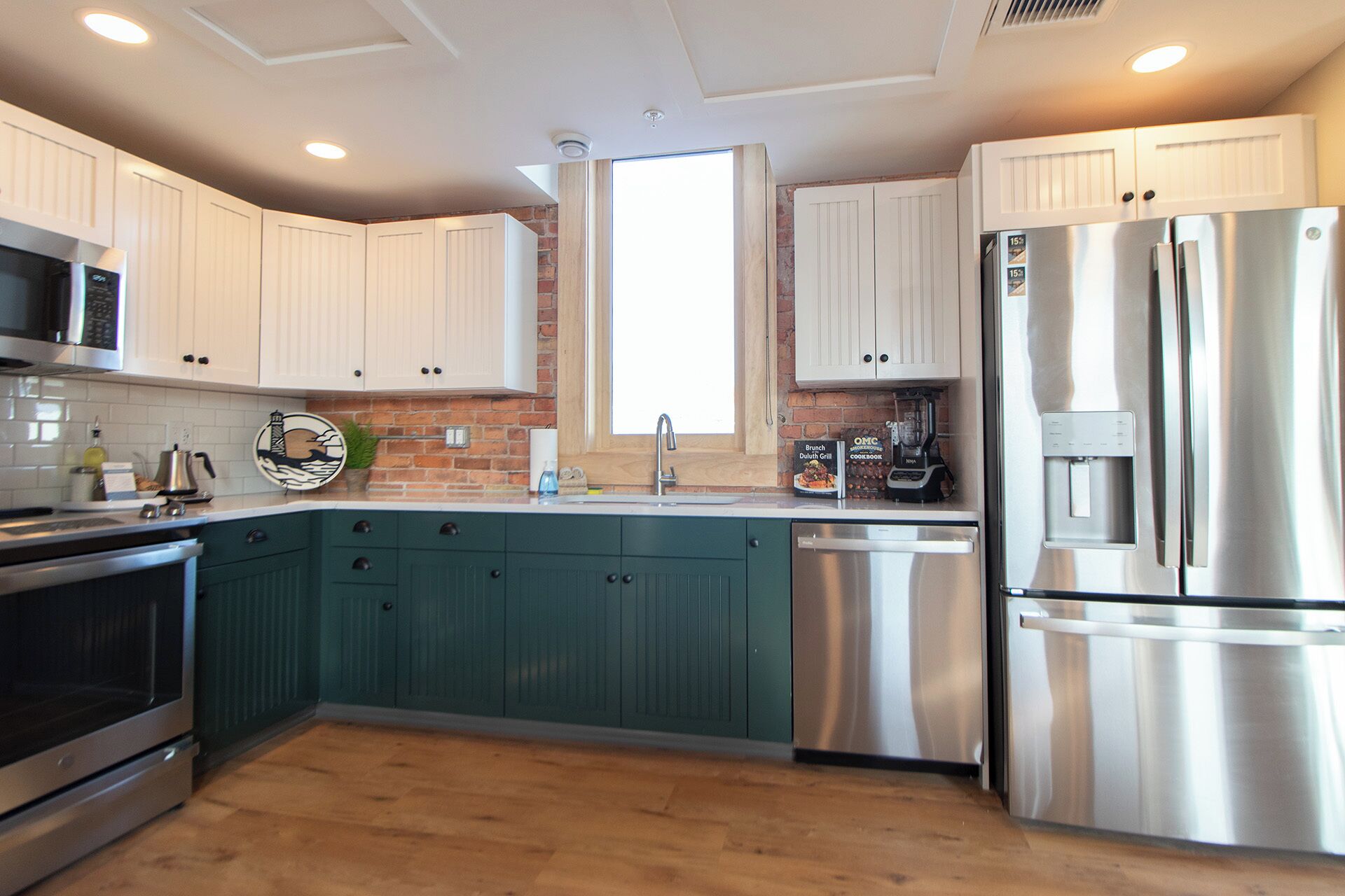 A modern kitchen with white cabinets, a stainless steel refrigerator, a microwave, and a dishwasher.