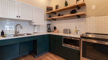 Una cocina moderna con armarios blancos, encimeras verde mar y electrodomésticos de acero inoxidable.
