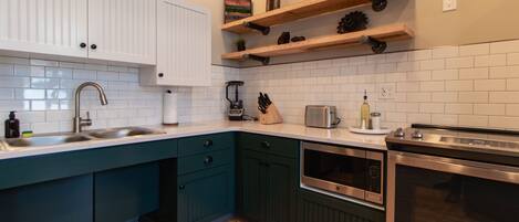 Une cuisine moderne avec des meubles blancs, un plan de travail de couleur turquoise et des appareils en acier inoxydable.