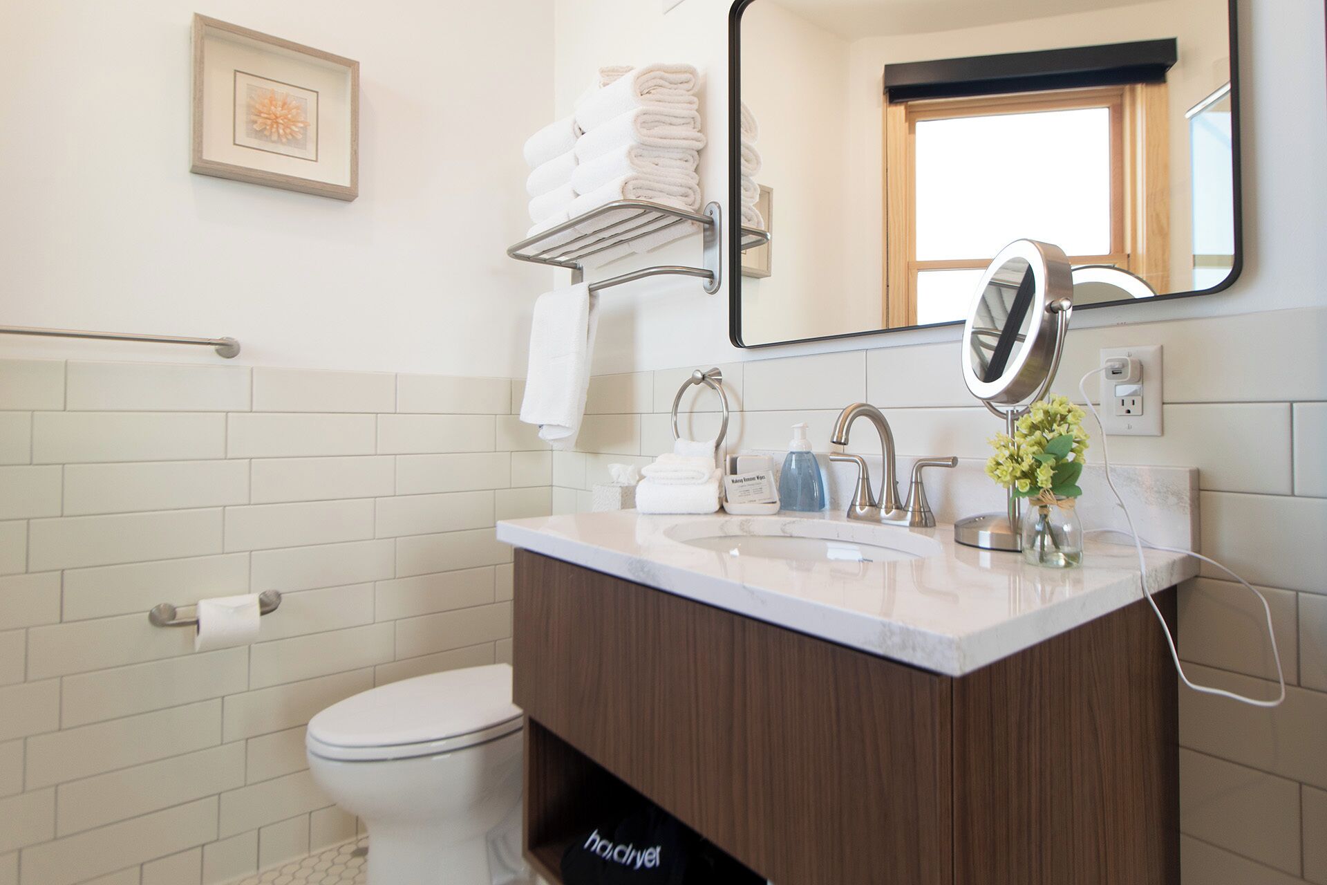 Une salle de bain comprenant des toilettes, un lavabo avec un miroir et un porte-serviettes.