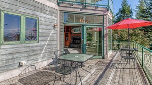 A wooden building with a balcony, outdoor seating, and a red umbrella. - Lower-level suite with deck/veranda, garden views, & foosball (Clinton)