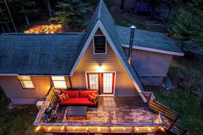 A house with a sloped roof, a red door, and a deck with outdoor seating.