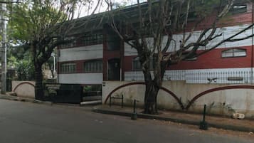 A building with a red and white facade, a gated entrance, and a tree in front.