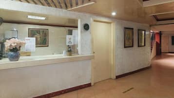 A reception area with a counter, framed artwork on the wall, and a door leading to another room.