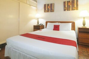 Una habitación de hotel con una cama grande, dos mesitas de noche con lámparas y obras de arte en las paredes.