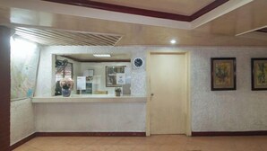 A reception area with a reception desk, a clock, and framed artwork on the wall. - RedDoorz @ Broadway Court Apartelle II Quezon City (Quezon City)