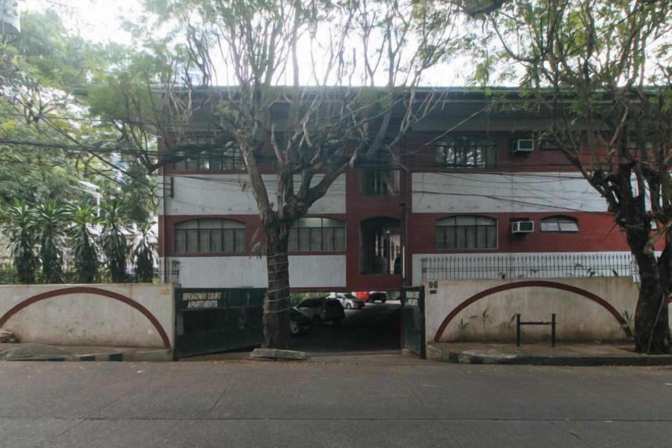 A building with a gated entrance, a parking area, and a fenced compound.