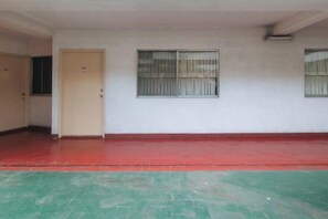 A room with a red floor, a beige door, and a window with metal bars. - RedDoorz @ Broadway Court Apartelle II Quezon City (Quezon City)