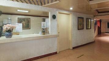 A reception area with a reception desk, a clock, framed pictures on the wall, and a tiled floor.