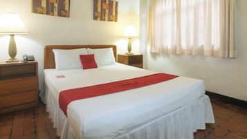 A hotel room with a large bed, two bedside tables, and a window with curtains.